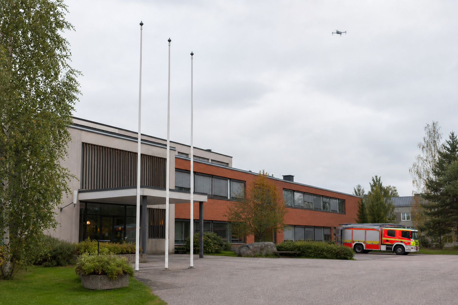 Kunnantalon yllä näkyy pieni drooni, taustalla pelastusajoneuvo rauhallisessa viranomaisympäristössä.