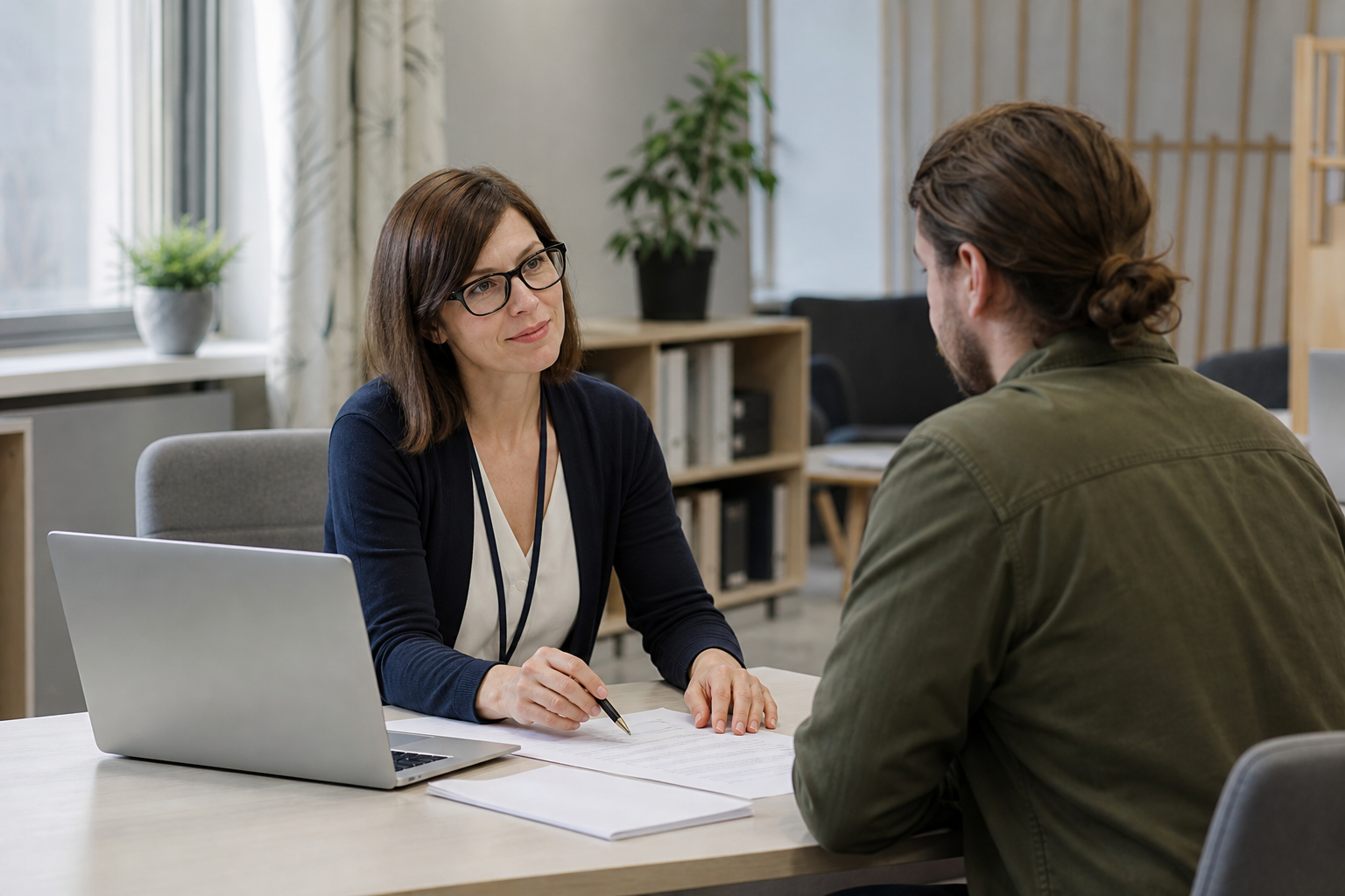Työnhakija ja uraohjaaja keskustelevat pöydän ääressä toimistomaisessa neuvontatilassa.