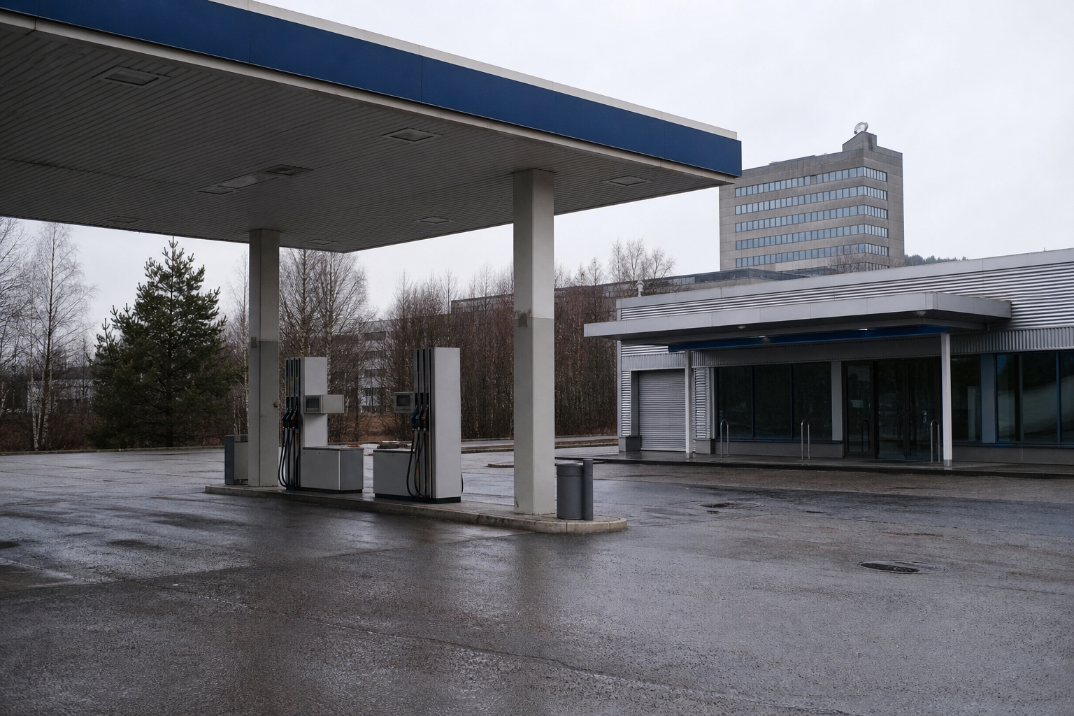 Nimetön huoltoasema ja kaupungin hallintorakennus pilvisessä suomalaisessa kaupunkiympäristössä.